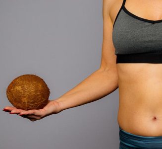 Lady in gym wear holding a coconut